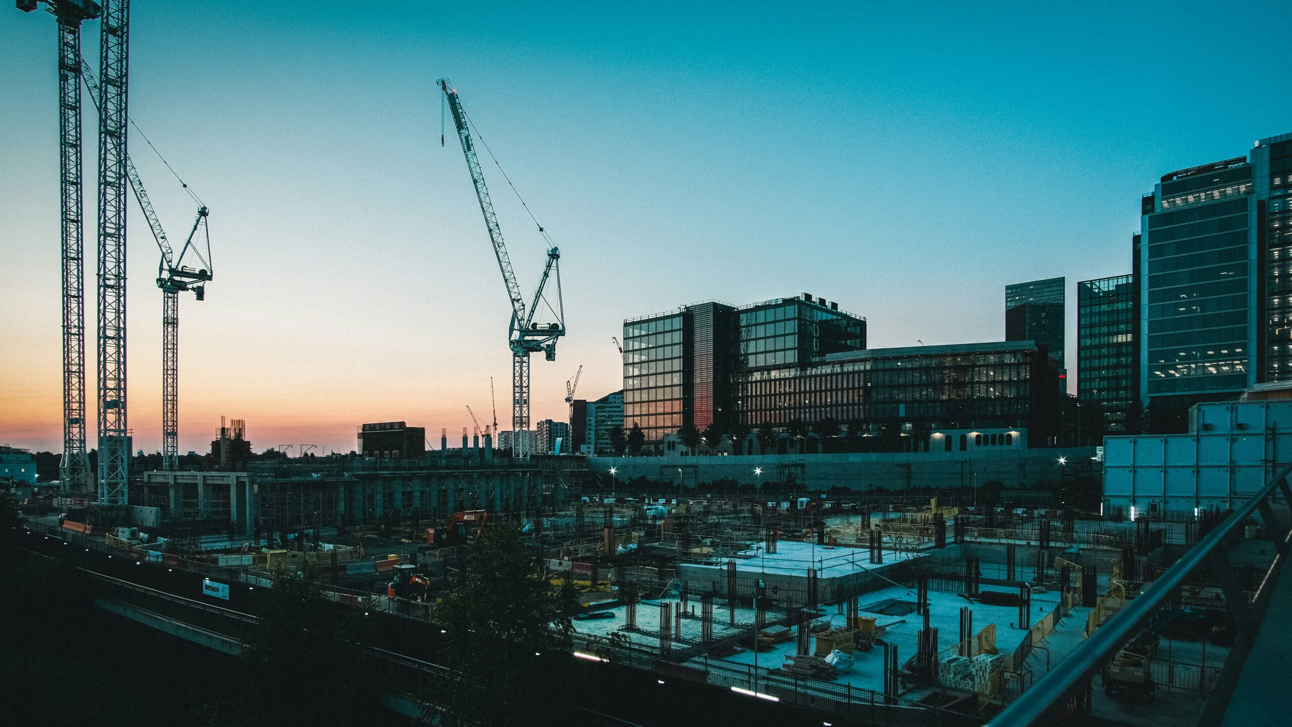 Großbaustelle mit Baukränen und moderner Architektur in der Abenddämmerung